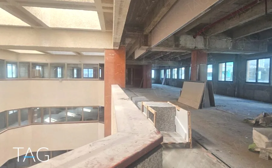 קומת משרדים פתוחה עם תקרת בטון חשופה וחלונות רצועה לאורך החזית, במשרד 3,000 מ