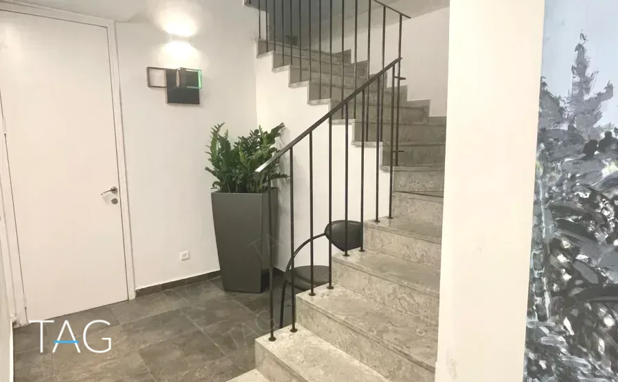 חדר מדרגות פנימי במשרד להשכרה ברחוב הוברמן תל אביב, מעקה מתכת שחור ורצפת אבן אפורה - תג נכסים