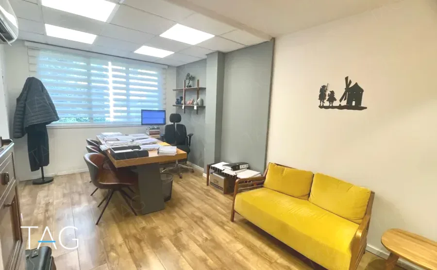 חדר עבודה במשרד להשכרה ברחוב הוברמן תל אביב, ספה צהובה, שולחן עבודה ורצפת פרקט - תג נכסים