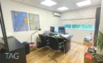 חדר מנהל במשרד להשכרה ברחוב הוברמן תל אביב, שולחן כהה, תמונות מופשטות וחלון עם תריס - תג נכסים