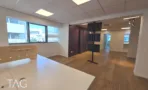 חדר ישיבות במשרד להשכרה ברחוב ליאונרדו דה וינצ'י תל אביב, שולחן לבן ארוך, מסכים וקיר בורדו - תג נכסים