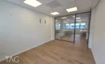 חדר עבודה מאחורי מחיצת זכוכית במשרד להשכרה ברחוב ליאונרדו דה וינצ'י תל אביב, מסגרות מתכת שחורות ורצפת אלון - תג נכסים