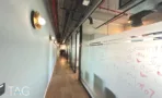 מסדרון עם לוח מחיק, תקרה טכנית חשופה ורצפת פרקט