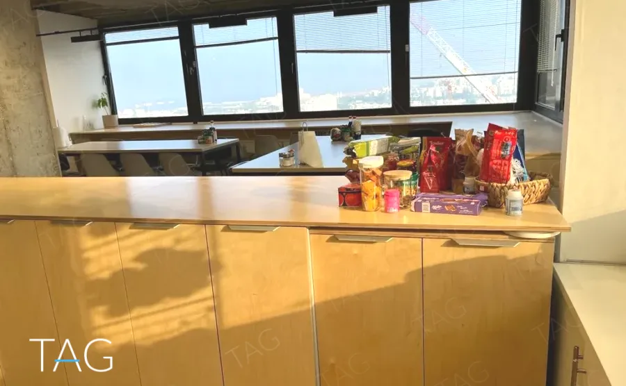 דלפק המטבח במשרד להשכרה במגדל המאה, מול חלונות רצועה עם נוף פתוח לעיר