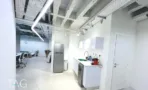 מטבחון קטן במשרד בבית אל על עם ארונות לבנים ומקרר