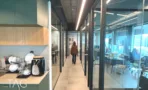 מסדרון עם מטבחון ירוק וחדרי זכוכית במשרד 230 מ״ר במגדל אקרו