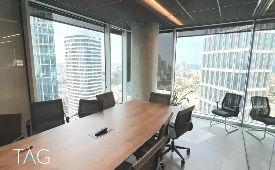 חדר ישיבות עם שולחן עץ ארוך ונוף למגדל עגול במשרד 230 מ״ר במגדל אקרו