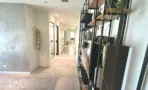 מסדרון עם קיר בטון מוחלק, מדפי מתכת שחורים וצמחייה