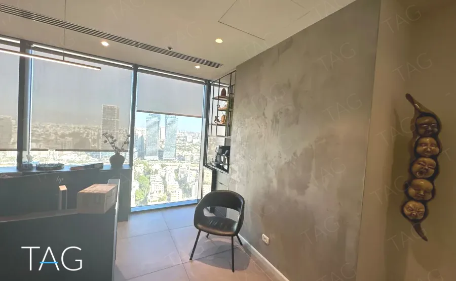 חדר עבודה עם נוף פנורמי של תל אביב וקיר בטון מוחלק