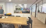משרד להשכרה 360 מ״ר במגדלי אלון, פינת אוכל עם שולחן עץ גדול ומטבחון מאובזר ברקע
