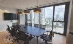 משרד להשכרה 242 מ״ר במגדלי אלון, חדר ישיבות עם שולחן ארוך, גופי תאורה תלויים וחלונות פנורמיים