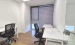 משרד להשכרה 360 מ״ר במגדלי אלון, חדר עבודה עם שני שולחנות לבנים וכיסאות שחורים ליד החלון