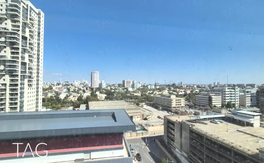 משרד להשכרה 360 מ״ר במגדלי אלון, נוף עירוני פתוח מהחלון עם מגדלי מגורים ושמיים כחולים