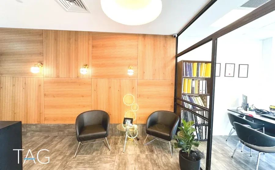 משרד להשכרה 130 מ״ר במגדל WE, פינת המתנה עם כורסאות וקיר מחופה עץ