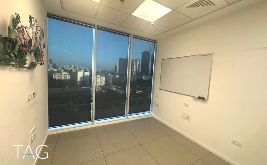 משרד להשכרה 100 מ״ר במגדל WE, חדר עבודה עם לוח מחיק וחלון לנוף העיר