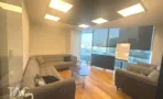 משרד להשכרה 280 מ״ר במגדל WE, פינת ישיבה עם ספות מול חלונות ונוף עירוני