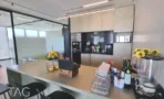 פינת מטבח ובר עם משטח אבן, מכונת קפה וכיסאות בר