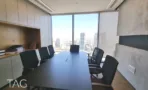 חדר ישיבות עם שולחן כהה, ארונות עץ וקיר בטון מוחלק