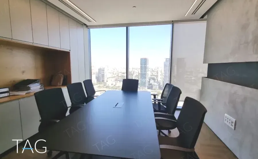 חדר ישיבות עם שולחן כהה, ארונות עץ וקיר בטון מוחלק