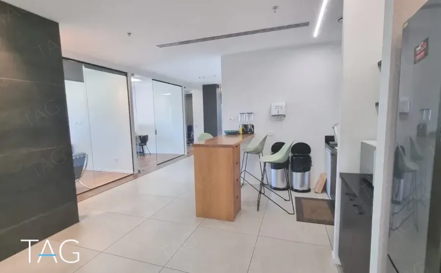 פינת מטבח עם רצפת אריחים בהירה, משטח עץ וכיסאות בר