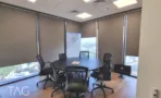 חדר ישיבות עם שולחן עגול, וילונות גלילה ונוף העיר