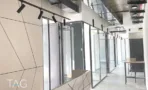 משרד להשכרה 270 מ״ר במגדל WE, מסדרון עם חדרי זכוכית ותאורת ספוטים שחורה