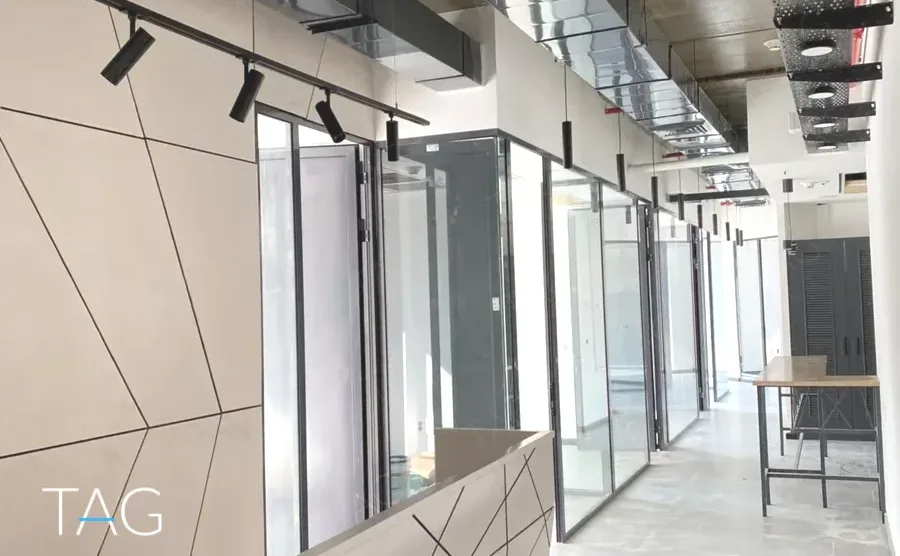 משרד להשכרה 270 מ״ר במגדל WE, מסדרון עם חדרי זכוכית ותאורת ספוטים שחורה