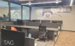 חלל עבודה פתוח במשרד להשכרה בבית עוז ברמת גן, שורות עמדות עם מחיצות ואיור קיר על מחיצת הזכוכית - תג נכסים