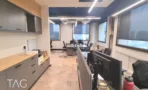 חלל עבודה במשרד להשכרה בבית עוז ברמת גן, ארונות עץ ואחסון תחתון לצד עמדות מחשב וחלונות רחבים - תג נכסים