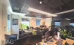 עמדות עבודה צפופות עם מסכים ושתילים, חלונות עם תריסים ותאורה ליניארית בתקרה כהה - משרד 890 מר, אריה שנקר מרכז גב ים הרצליה - תג נכסים