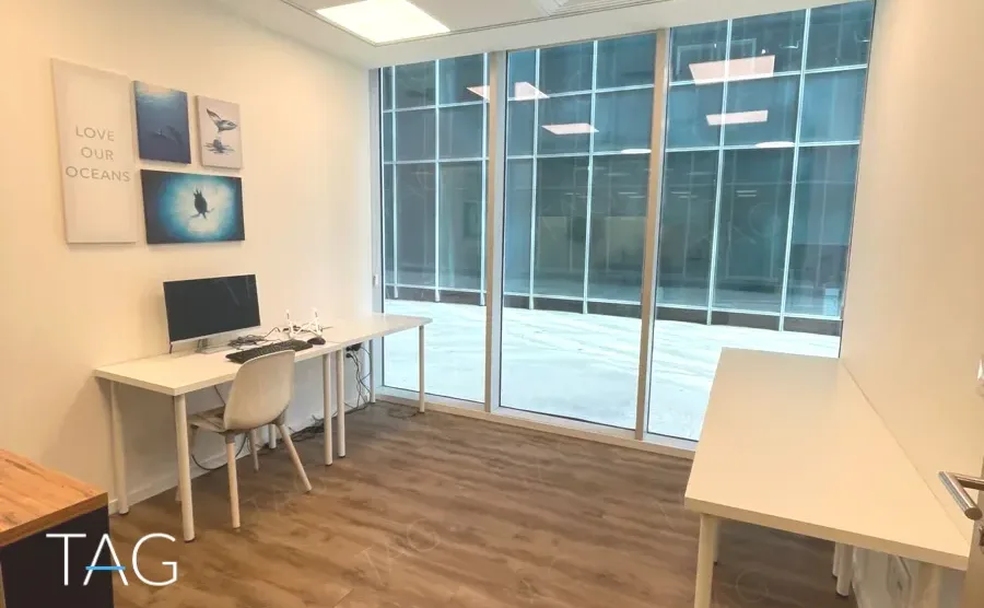 משרד להשכרה 176 מ״ר במגדל WE, חדר עבודה מואר עם שולחנות לבנים וקיר זכוכית