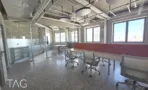 חלל עבודה פתוח עם רצפת טרצו, ספסל אדום ארוך וחלונות אל העיר, במשרד 300 מ