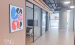 מסדרון עם עמוד עגול וחדרים מזוגגים במשרד 741 מ