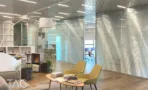 אזור פתוח במשרד להשכרה במגדל אדגר 360C - פינת ישיבה עם כורסאות חרדל מול מחיצות זכוכית עם תריסים משולבים - תג נכסים
