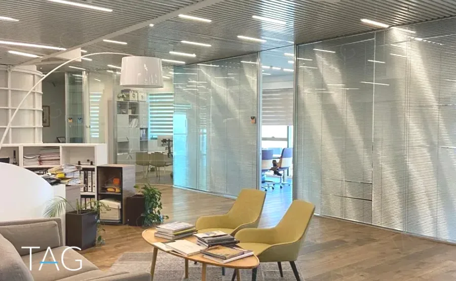 אזור פתוח במשרד להשכרה במגדל אדגר 360C - פינת ישיבה עם כורסאות חרדל מול מחיצות זכוכית עם תריסים משולבים - תג נכסים