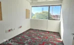 חדר ריק עם חלון שנשקפים ממנו עצים, שטיח מודולרי מודפס ולוח מודעות על הקיר - משרד 918 מר, אריה שנקר מרכז גב ים הרצליה - תג נכסים