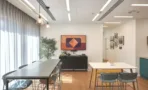 אזור ישיבה עם שולחנות, תמונת קיר צבעונית ותאורה תלויה