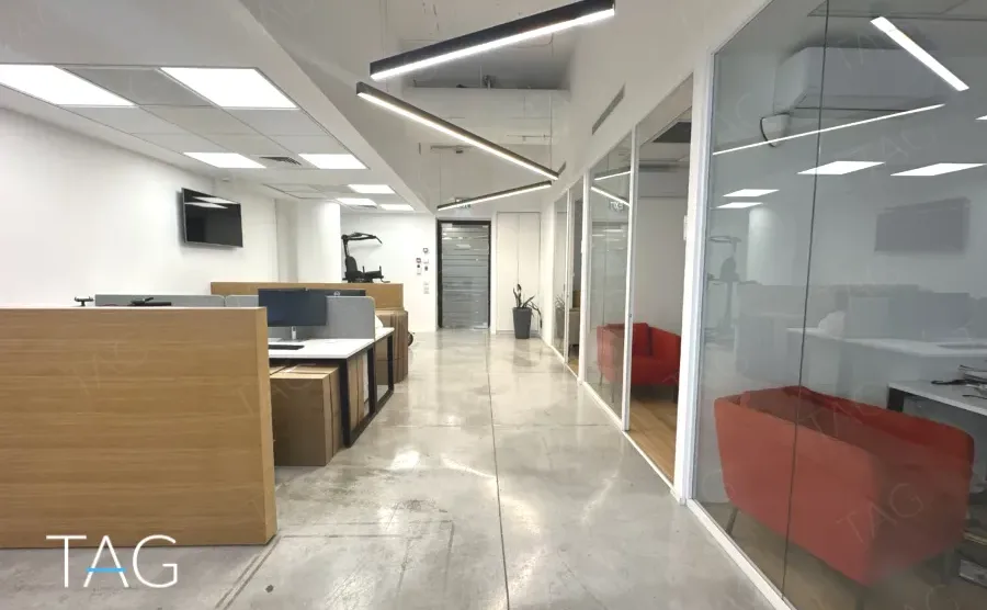 מעבר עם מחיצות זכוכית ותאורה לינארית במשרד להשכרה ליד רכבת השלום - תג נכסים