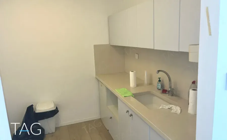 מטבח עם כיור ומשטח בז וארונות לבנים במשרד במגדל שלום מאיר