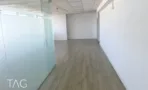 חלל ריק עם מחיצת זכוכית לכל האורך ופרקט בהיר במשרד במגדל שלום מאיר