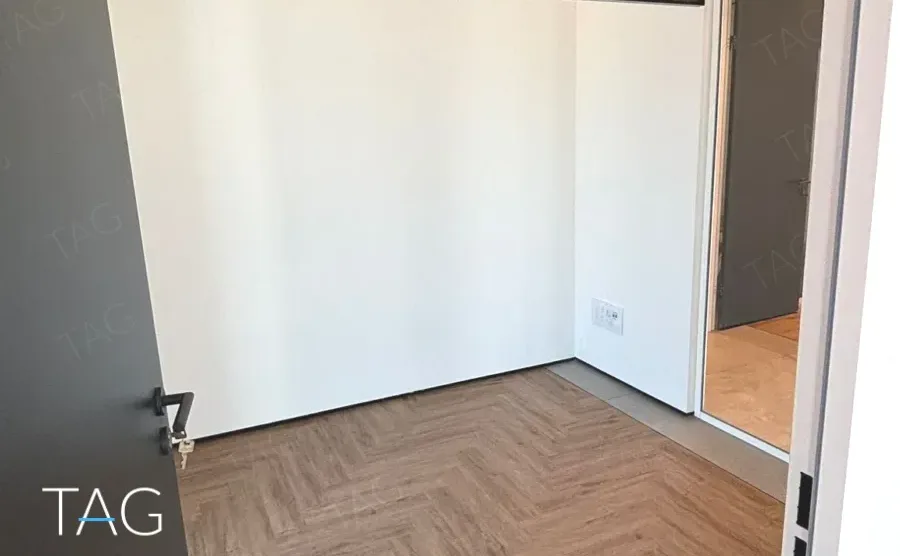 חדר בACRO BUSINESS CAMPUS עם פרקט אדרה, דלת שחורה ופתח למסדרון - תג נכסים