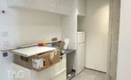 מטבחון בACRO BUSINESS CAMPUS עם ארונות לבנים, מקרר משולב ועמוד בטון - תג נכסים