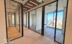 מסדרון עם תקרת שלבי עץ וחדרי זכוכית במשרד במגדל אייקון
