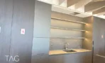 מטבח משרדי בACRO BUSINESS CAMPUS עם חיפוי עץ כהה, מדפים מוארים ומשטח אבן - תג נכסים