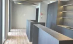 חלל משרדי בACRO BUSINESS CAMPUS עם דלפקים כהים, מדפים מוארים ותקרה מעוצבת - תג נכסים