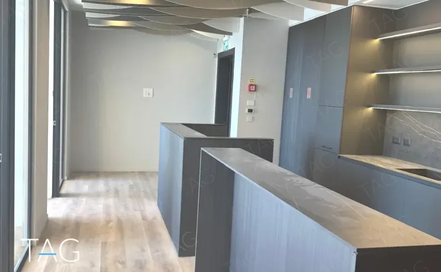 חלל משרדי בACRO BUSINESS CAMPUS עם דלפקים כהים, מדפים מוארים ותקרה מעוצבת - תג נכסים