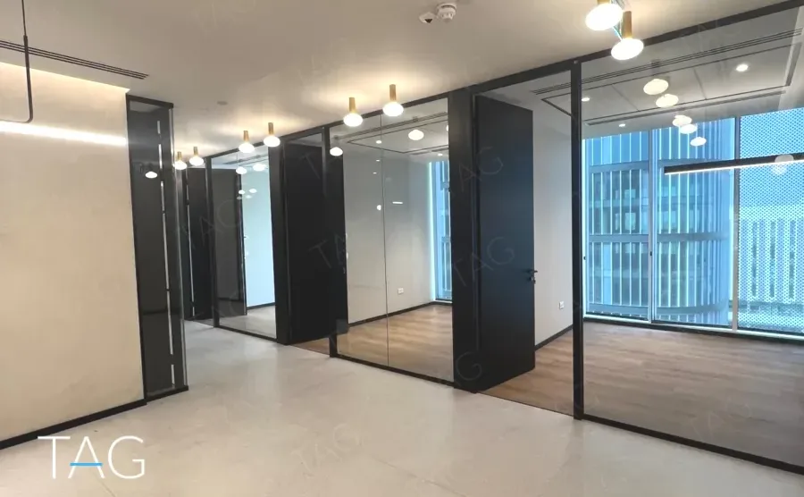 חלל משרדי בACRO BUSINESS CAMPUS עם חדרי זכוכית, דלתות שחורות ותאורה תלויה - תג נכסים