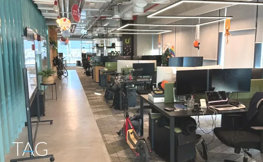 חלל עבודה פתוח עם עמדות, וילון טורקיז ורצפת בטון