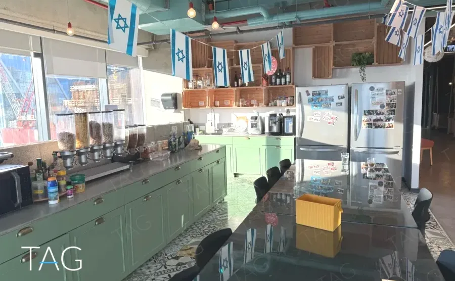 מטבח גדול עם ארונות ירוקים ורצפת טרצו