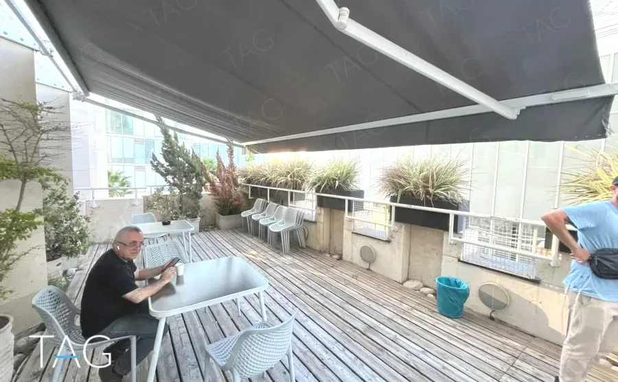מרפסת גג משותפת עם דק עץ, גגון ואדניות במגדל יובנק UBANK תל אביב